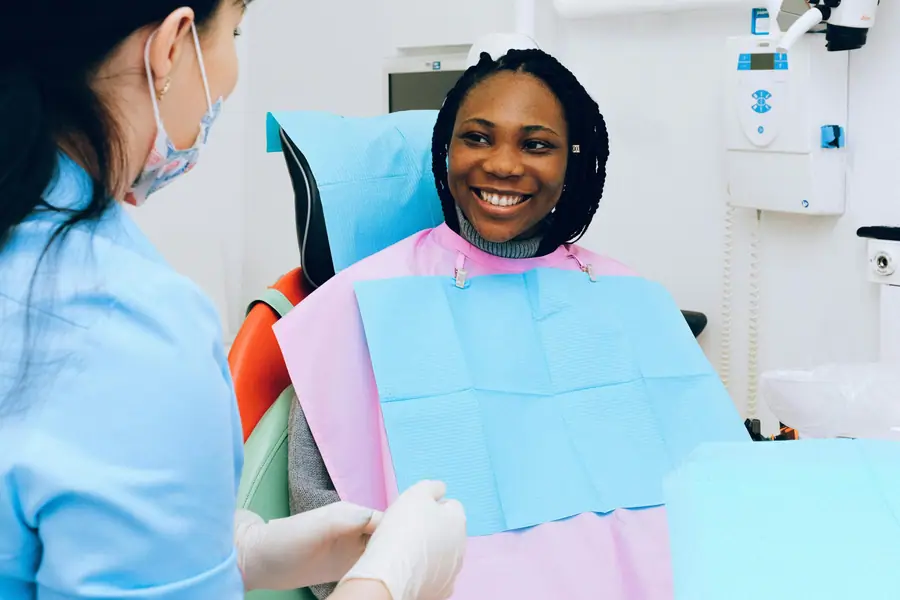 Odontoiatra e assistente durante una seduta con una paziente sorridente