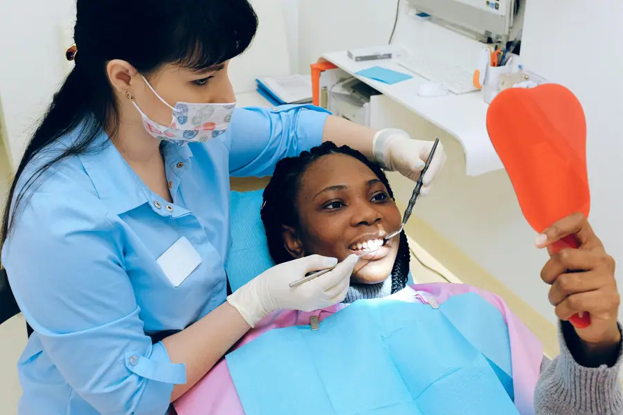 Trattamento odontoiatrico con la paziente che tiene lo specchio